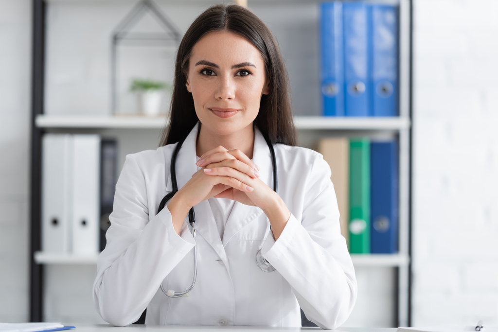 Brunette doctor looking at camera in clinic  - Photo, Image