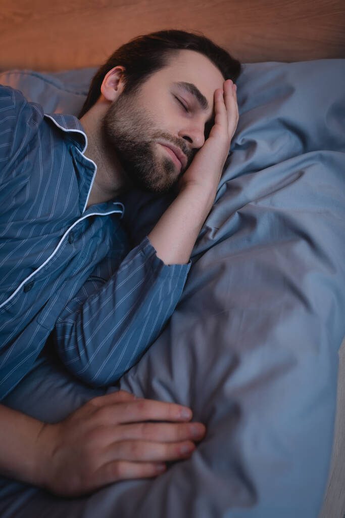 Bärtiger Mann leidet an Schlaflosigkeit im heimischen Bett  - Foto, Bild