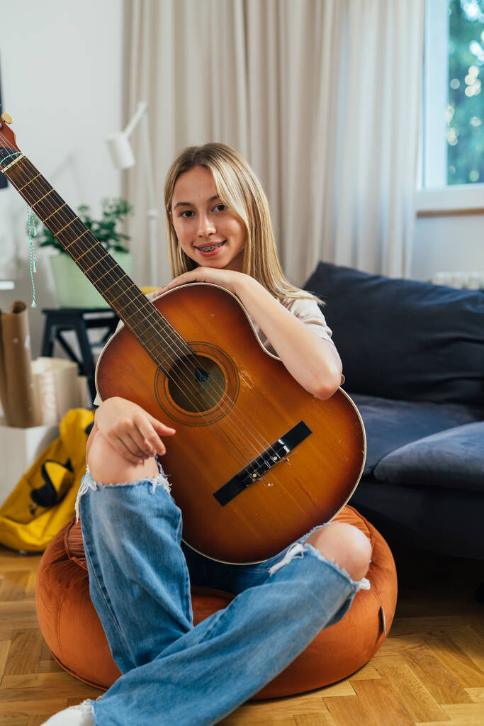 teenager caucasian girl posing with her guitar sitting at home - Fotó, kép
