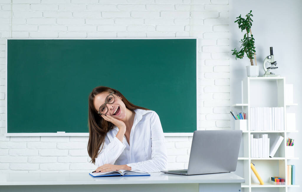Portret van een lachende jonge student die studeert met een laptop in de klas. Online leren op school, afstandsonderwijs - Foto, afbeelding