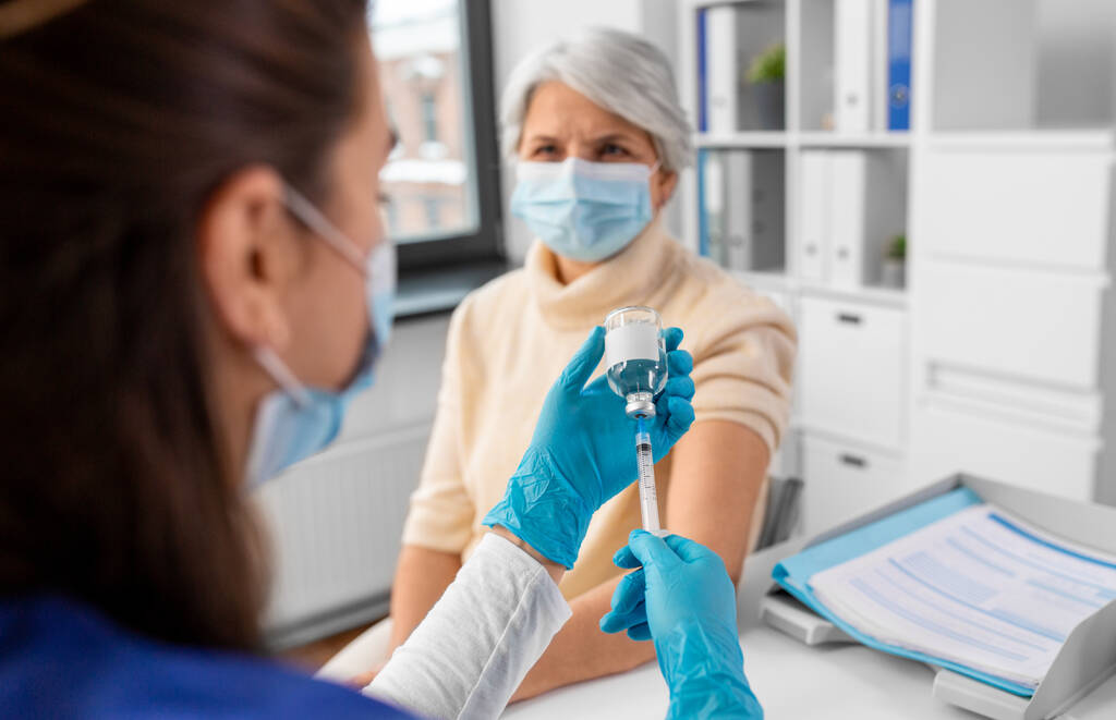 医学、健康と予防接種の概念-病院でマスク中の医師または看護師の充填注射器の閉鎖 - 写真・画像