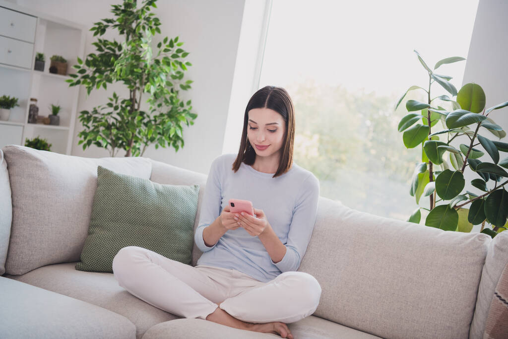 Portret atrakcyjnej dziewczyny siedzi na divan za pomocą urządzenia gadżet web wi-fi w domu mieszkanie w domu. - Zdjęcie, obraz