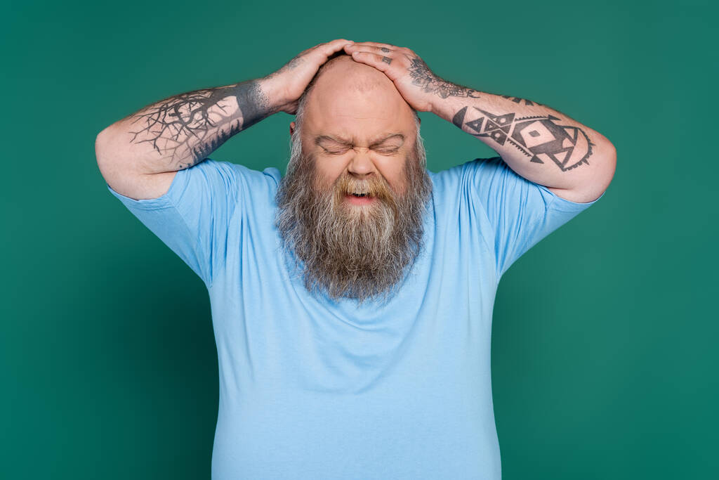 upset bearded man with overweight touching bald head isolated on green - Photo, Image
