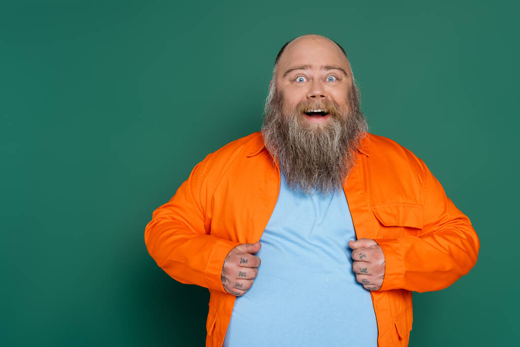 amazed overweight man with beard looking at camera isolated on green - Foto, Bild