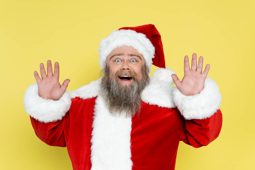 asombrado hombre de tamaño grande en traje de navidad agitando las manos aisladas en amarillo - Foto, Imagen