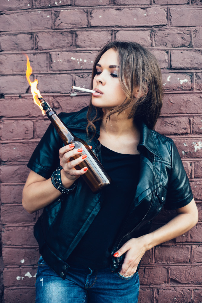 Böses Mädchen zündet sich Zigarette aus Molotowcocktail-Bombe in der Hand an - Foto, Bild