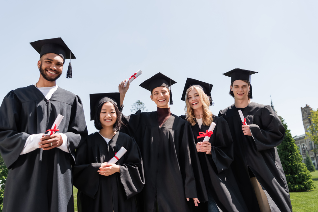 Multicultural bachelors holding diplomas outdoors  - Foto, Imagem