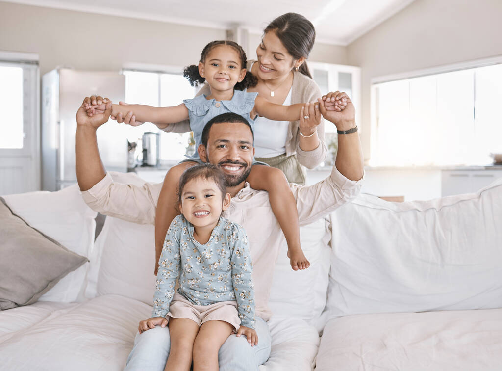 Feliz joven familia de raza mixta sonriendo buscando alegre y relajante en el sofá juntos en casa. Dos padres hispanos disfrutando de un día con sus hijos pequeños en casa uno el fin de semana. - Foto, imagen