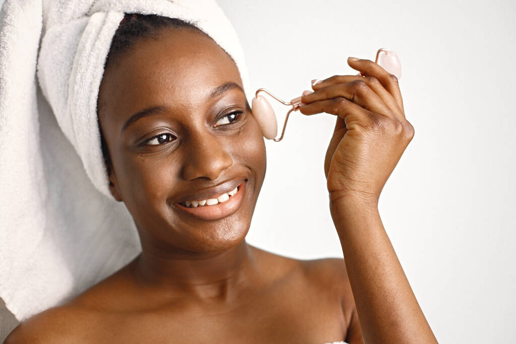 Black young woman isolated on white background. Girl has her hair wrapped in a towel. Black woman enjoy after body treatment. - Foto, Imagen