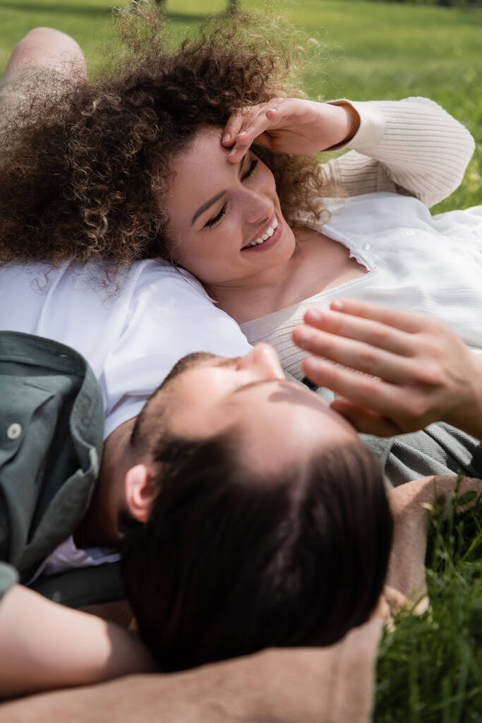 cheerful woman lying with happy boyfriend during picnic in summer park - Zdjęcie, obraz