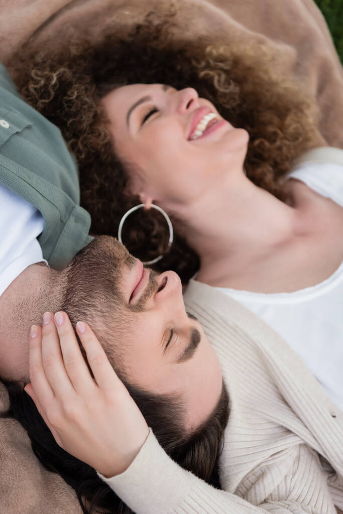 top view of pleased young woman and man with closed eyes lying on soft blanket  - 写真・画像