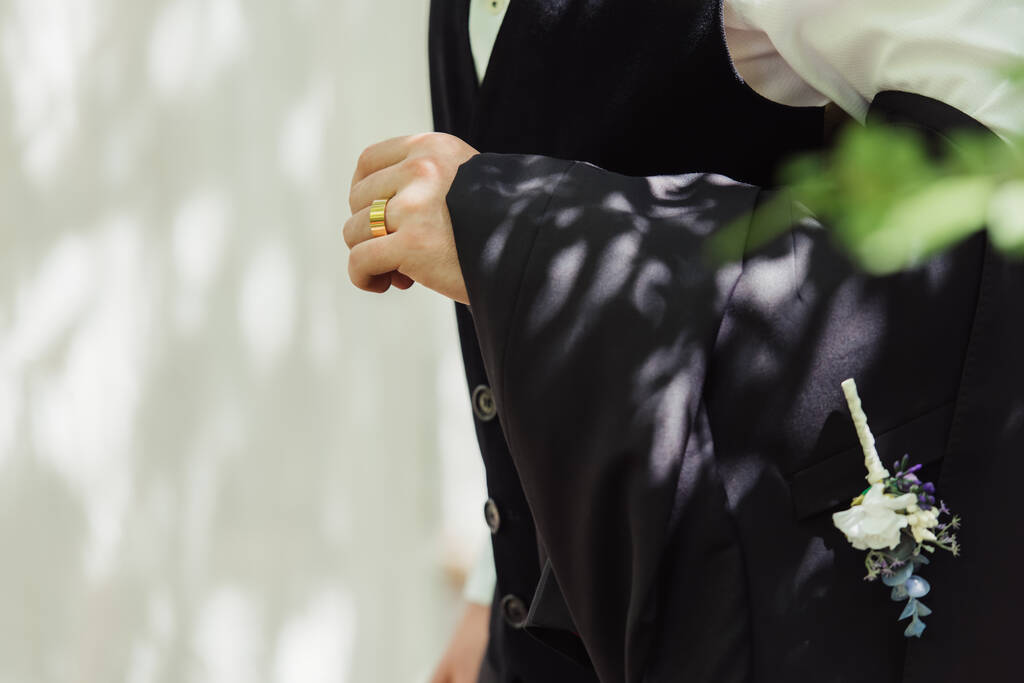 cropped view of groom in formal wear with golden wedding ring on finger - Valokuva, kuva