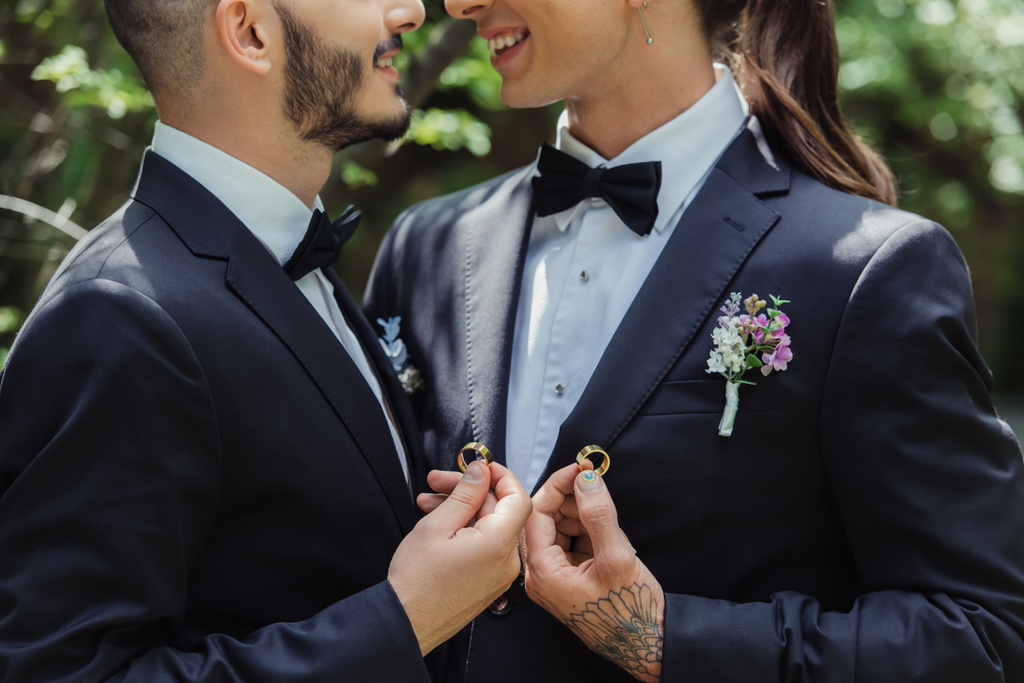 cropped view of happy gay couple holding wedding rings in hands  - 写真・画像