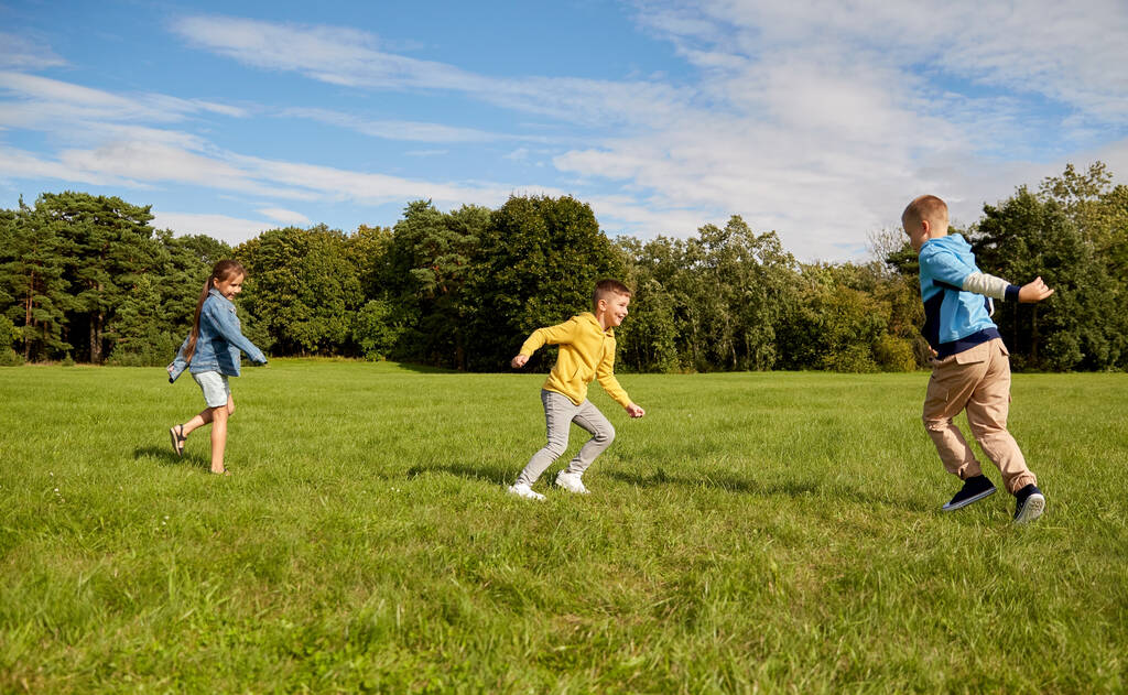 infanzia, tempo libero e concetto di persone - gruppo di bambini felici che giocano a tag game e corrono al parco - Foto, immagini