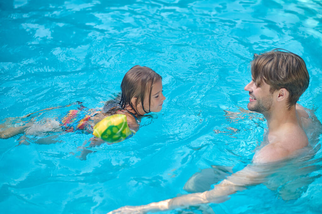 In una piscina. Papà e figlia nuotano insieme in una piscina - Foto, immagini