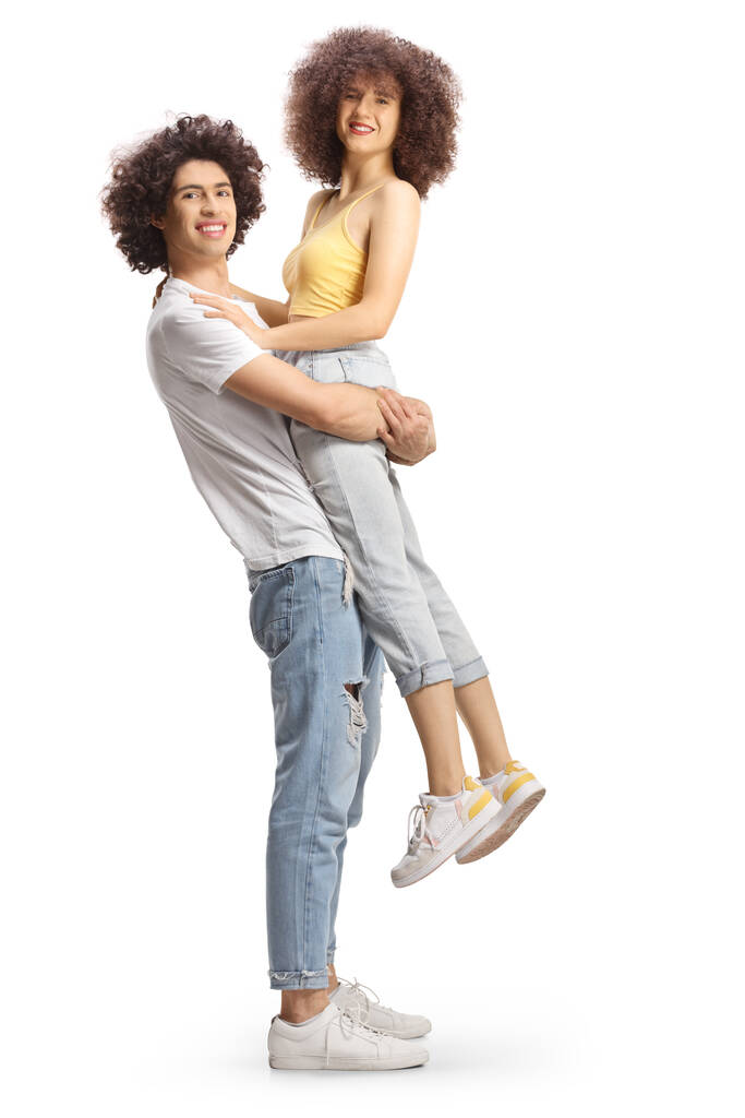 Full length side shot of a guy with curly hair lifting a girl isolated on white background - Zdjęcie, obraz