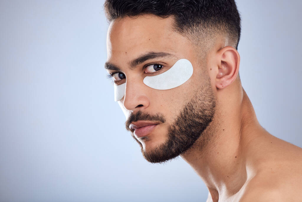 Shot of a handsome young man wearing under eye patches against a studio background. - 写真・画像
