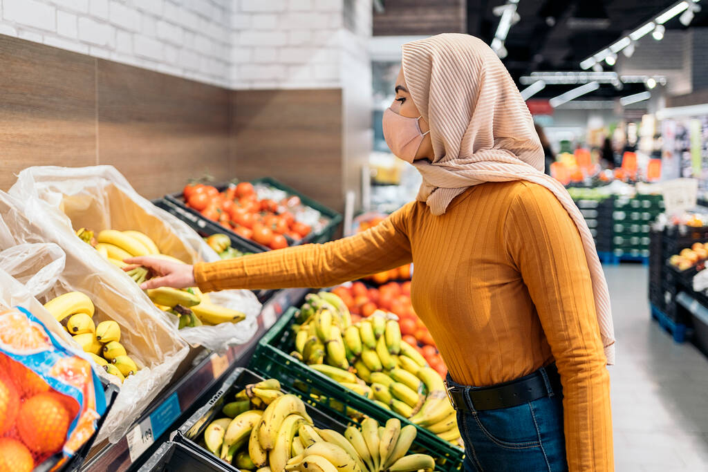 Young muslim woman wearing protective face mask buying fruit in the groceries shop. - Photo, Image