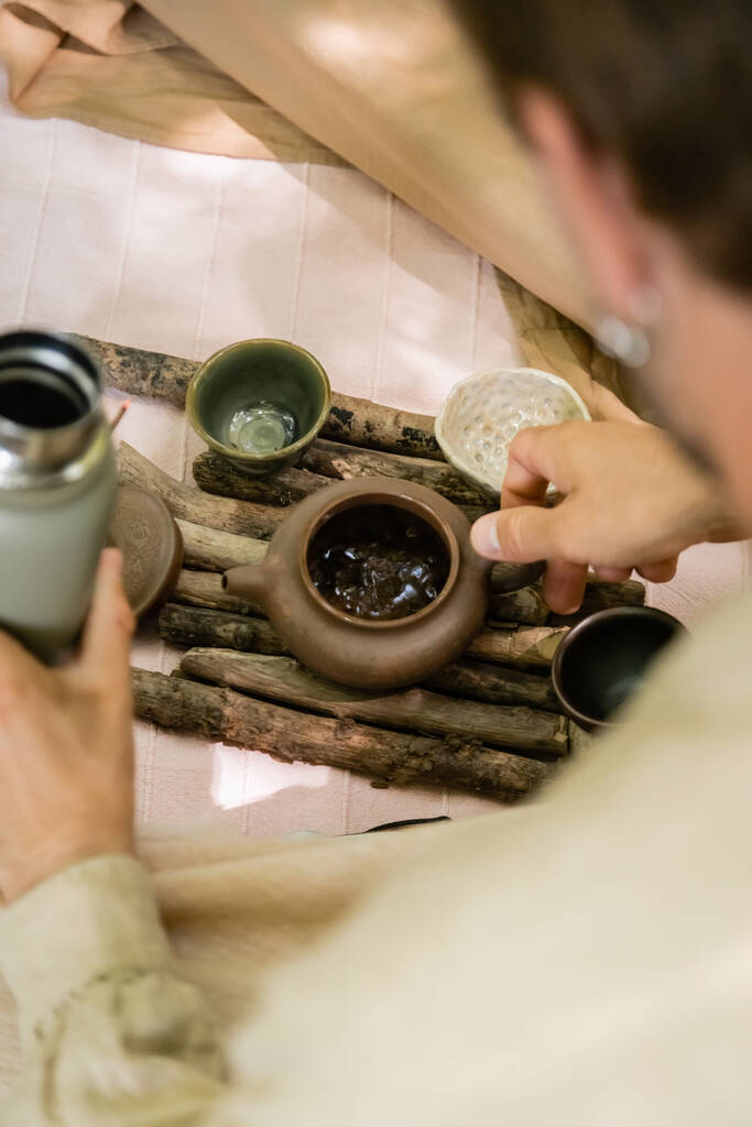 Vágott kilátás elmosódott ember kezében termosz és teáskanna a takarón a szabadban  - Fotó, kép
