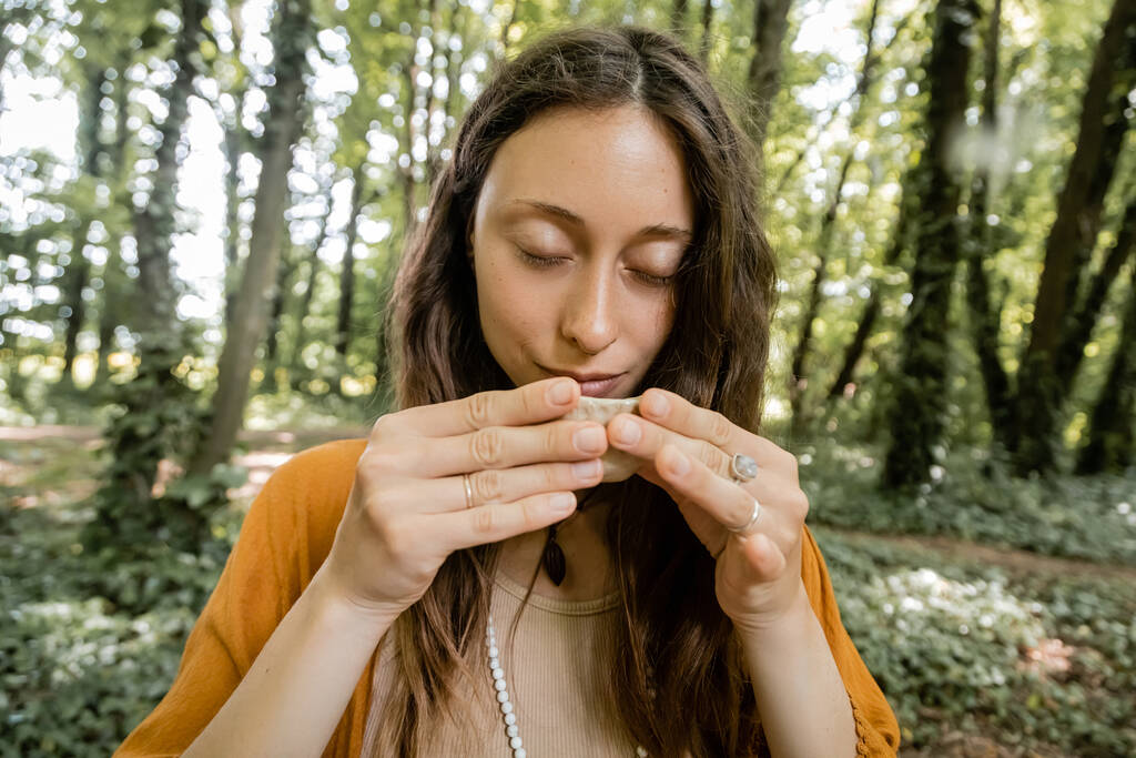 Brunette woman holding tea bowl in forest  - Zdjęcie, obraz