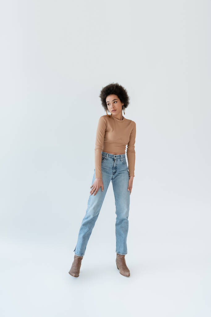 Afrikanische Amerikanerin in Jeans und Cowboystiefeln auf grauem Hintergrund - Foto, Bild