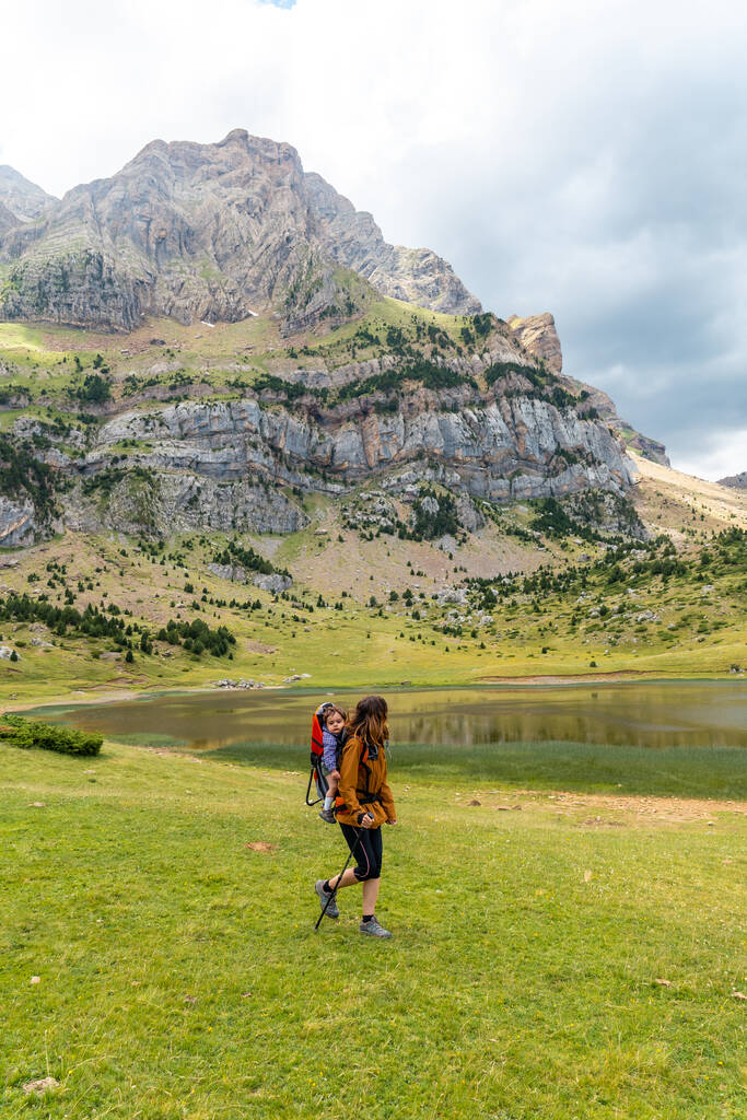 Woman with her son in the backpack in the Ibon de Piedrafita, Tena valley in the Pyrenees, Huesca - Foto, immagini