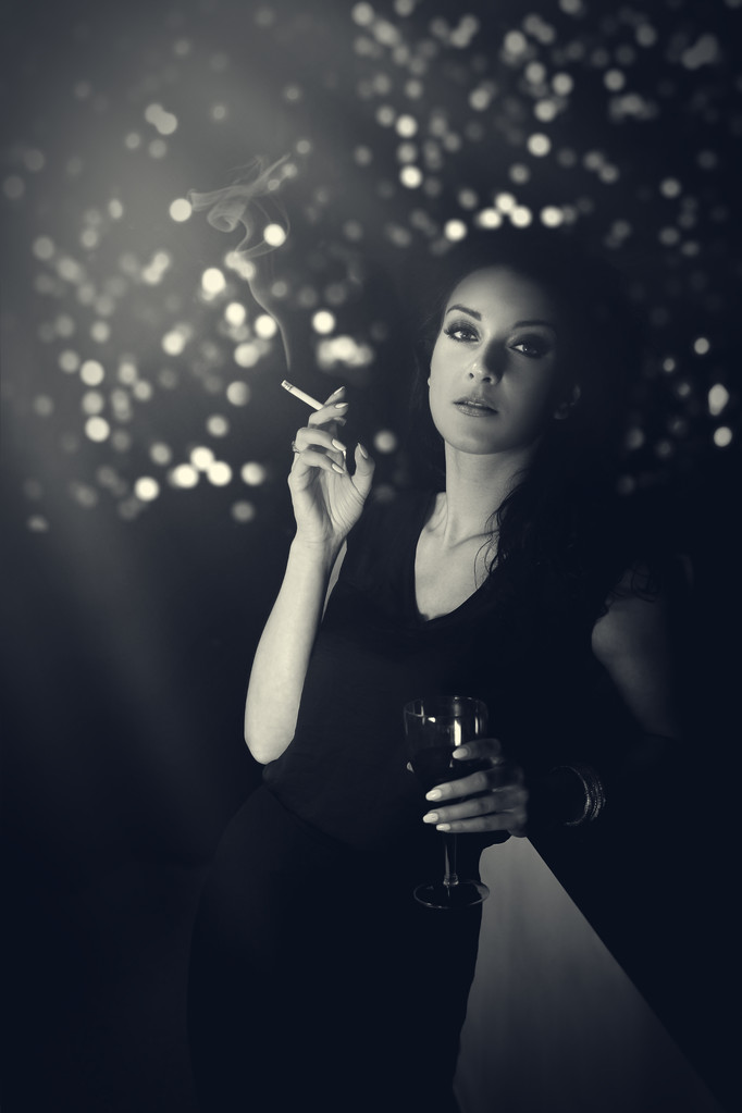 Hauntingly mooie vrouw permanent met een sigaret in avondjurk aan de bar - Foto, afbeelding