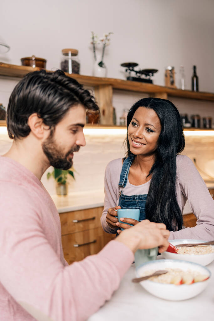 Smiley black woman and her boyfriend having delicious breakfast in the kitchen at home. - Foto, Imagen