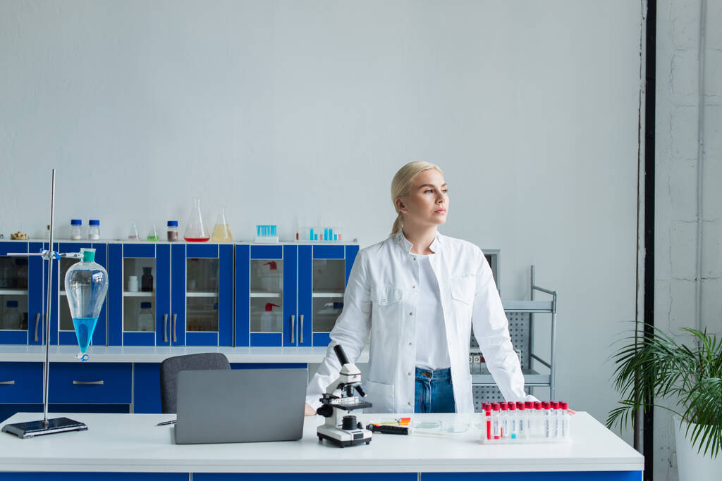 Scientist standing near laptop and microscope in laboratory  - Foto, imagen