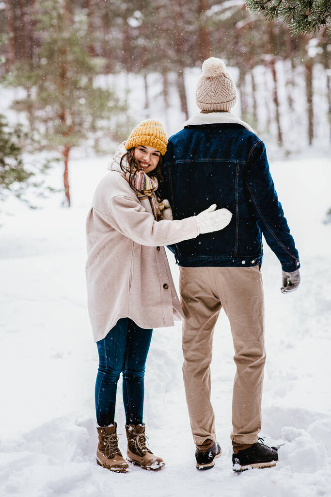 人と愛とレジャーのコンセプト-幸せな笑顔のカップルが冬の森を歩く - 写真・画像
