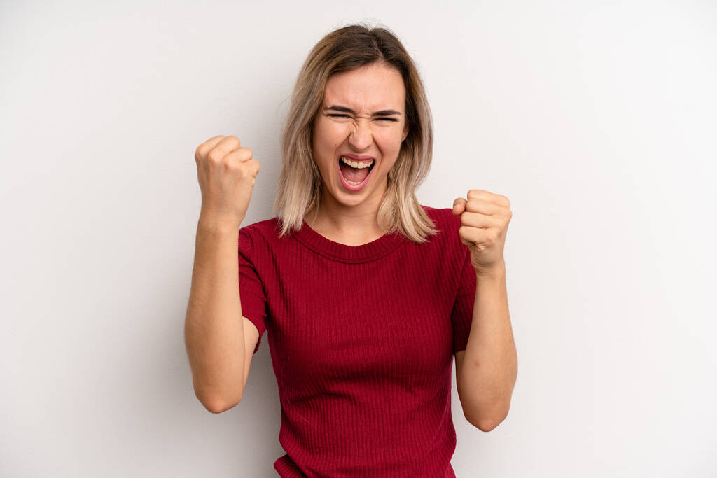 young adult blonde woman feeling happy, positive and successful, celebrating victory, achievements or good luck - Photo, image