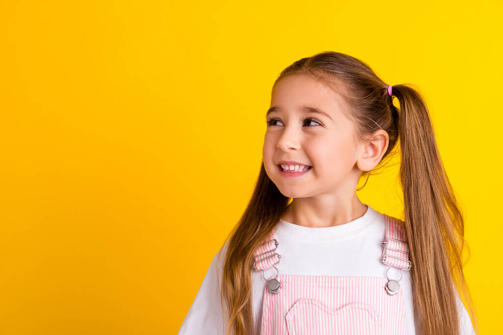 Foto van dromerige charmante school meisje dragen zomer outfit op zoek lege ruimte geïsoleerde gele kleur achtergrond. - Foto, afbeelding