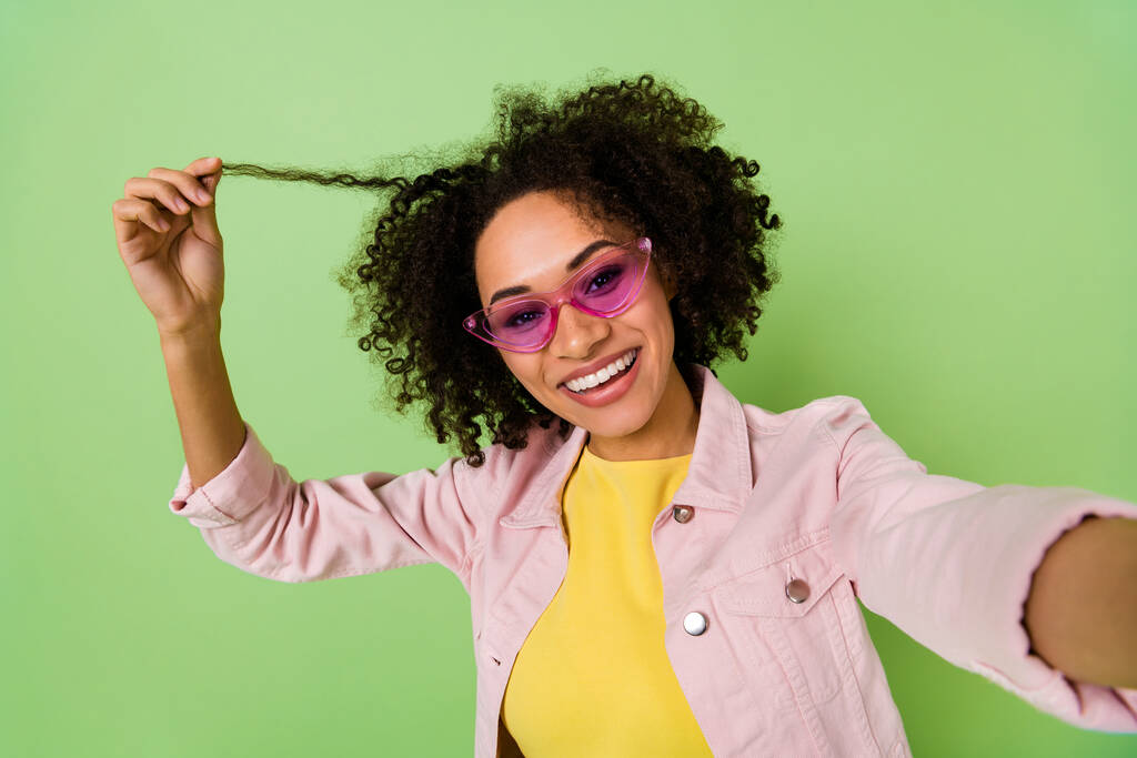 Πορτρέτο της ελκυστικής δροσερό κορίτσι λάβει selfie χέρι κρατήστε το παιχνίδι hairdo μπούκλα απομονώνονται σε πράσινο χρώμα φόντο. - Φωτογραφία, εικόνα
