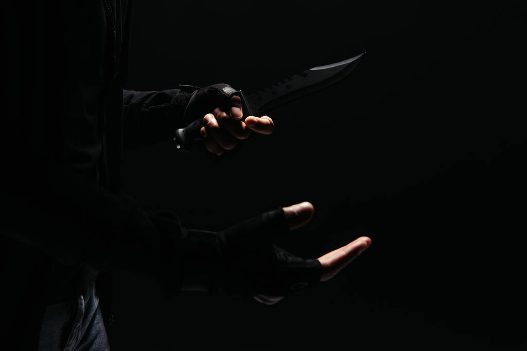 Vista recortada de bandido afroamericano en guantes con cuchillo aislado en negro  - Foto, imagen