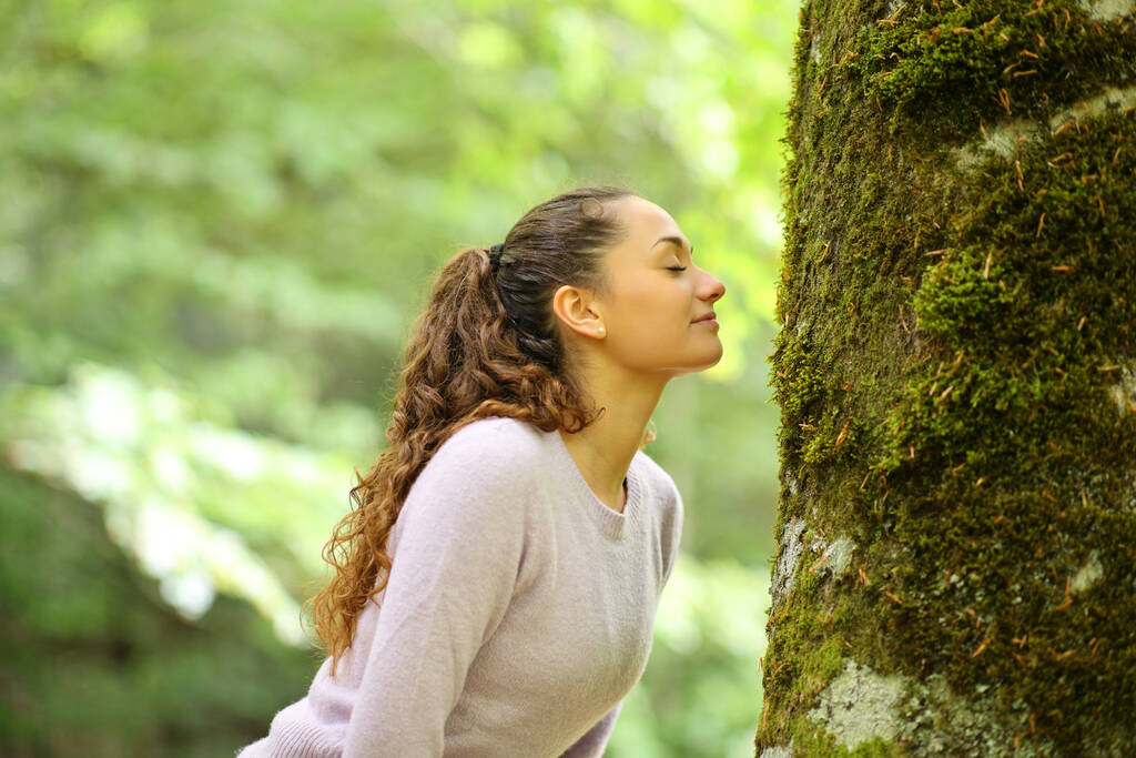 Προφίλ μιας ευτυχισμένης γυναίκας που μυρίζει βρύα σε ένα δέντρο σε ένα δάσος - Φωτογραφία, εικόνα