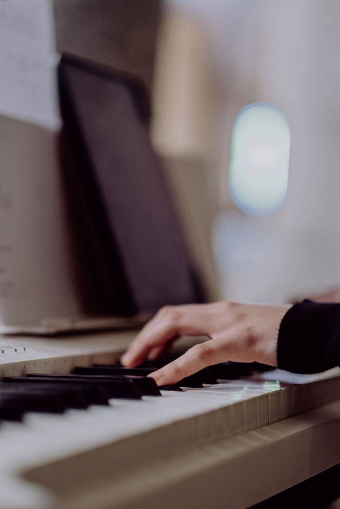 Um close-up de uma mão em um teclado de piano com um fundo embaçado - Foto, Imagem
