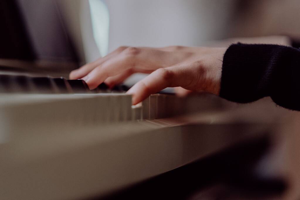 Крупный план руки на клавиатуре пианино с размытым фоном - Фото, изображение