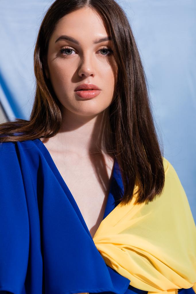 retrato de jovem mulher ucraniana com olhos azuis olhando para a câmera em azul - Foto, Imagem