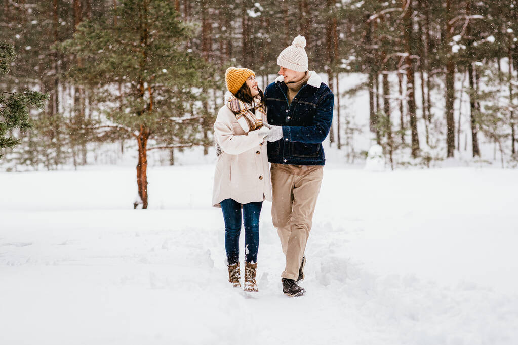 emberek, szerelem és szabadidő koncepció - boldog mosolygós pár sétál a téli erdőben - Fotó, kép