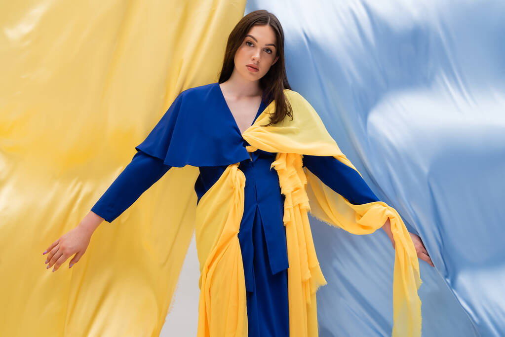 modello ucraino patriottico in abito alla moda in posa vicino drappeggio blu e giallo - Foto, immagini