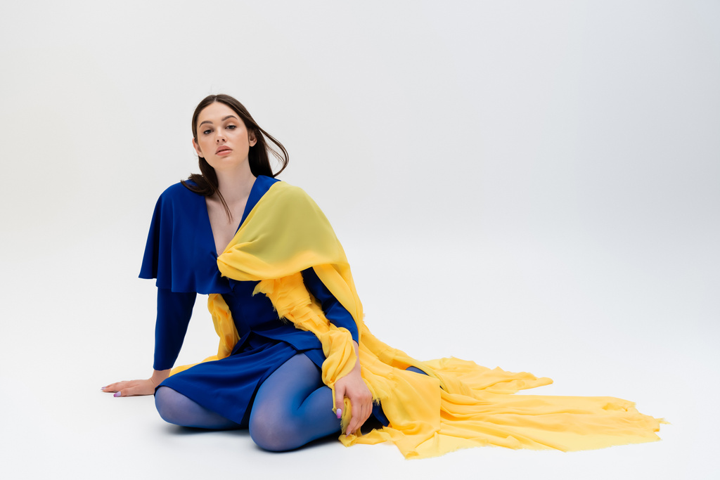 confident anf patriotic ukrainian young woman in blue and yellow outfit posing on grey - Zdjęcie, obraz