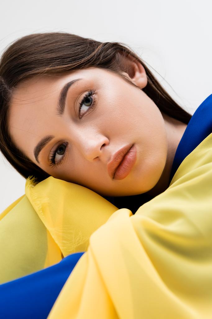 tender ukrainian young woman in blue and yellow outfit looking away isolated on grey - Foto, afbeelding