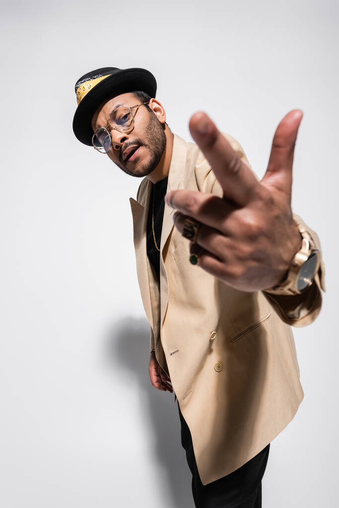 szakállas keleti hip-hop előadó fedora kalap és szemüveg gesztikuláló szürke - Fotó, kép