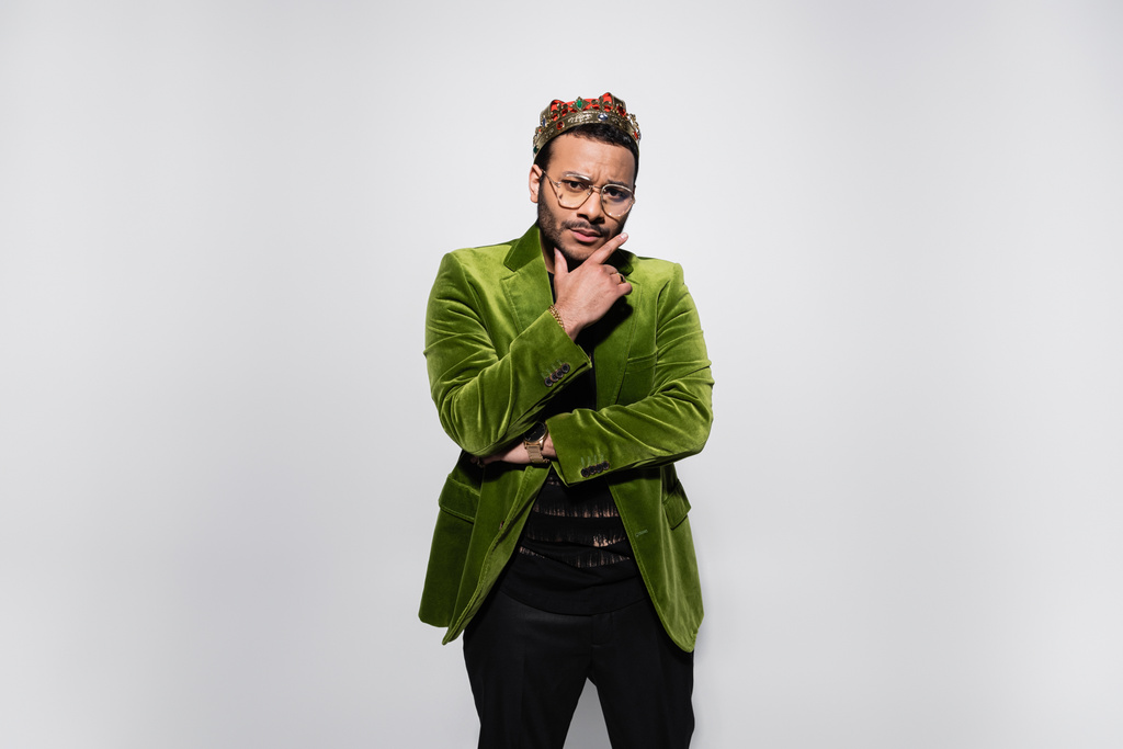 zamyšlený hip hop zpěvák v zeleném sametovém saku a koruně izolovaný na šedé - Fotografie, Obrázek