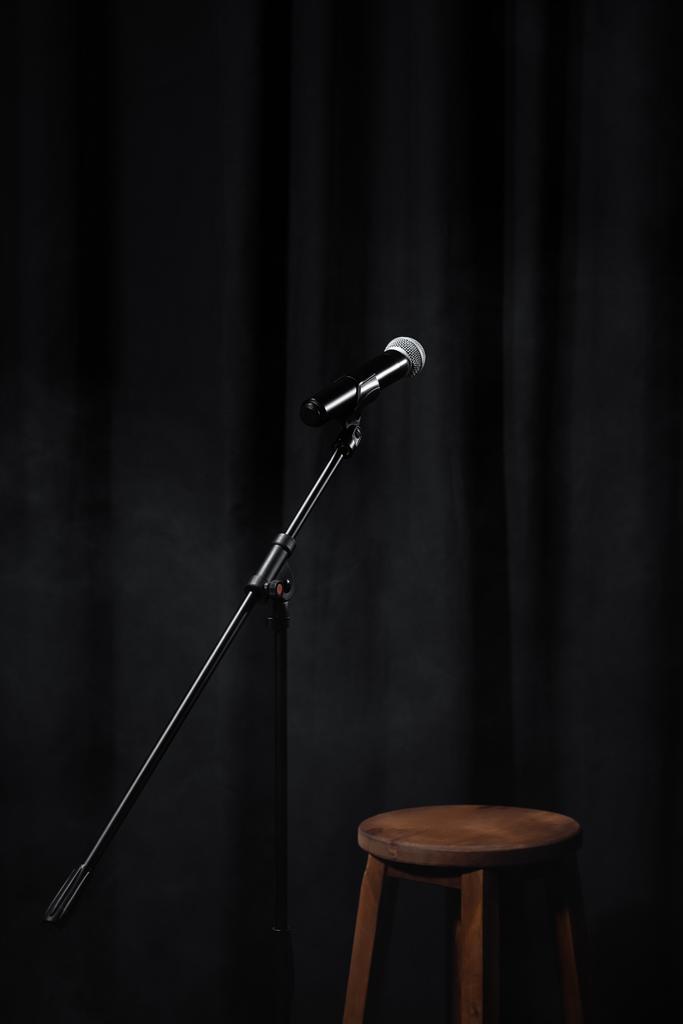 mikrofon na stojanu na černém jevišti se závěsem a dřevěnou židlí - Fotografie, Obrázek