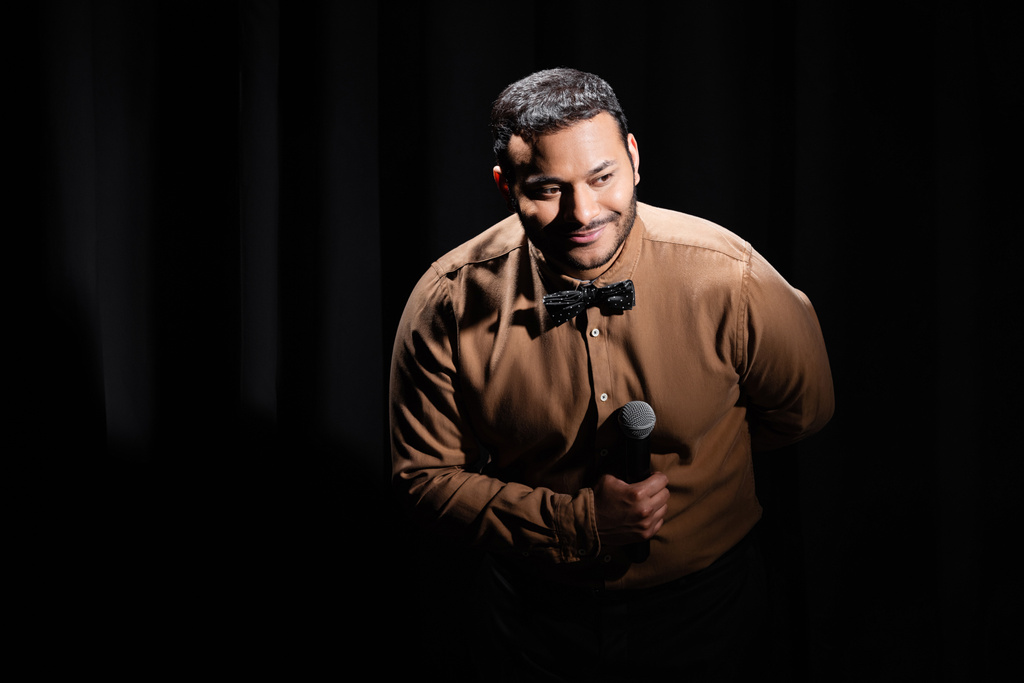 pleased middle east comedian performing stand up comedy into microphone on black  - Photo, Image