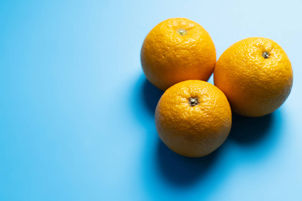Vista superior de laranjas no fundo azul com sombra  - Foto, Imagem