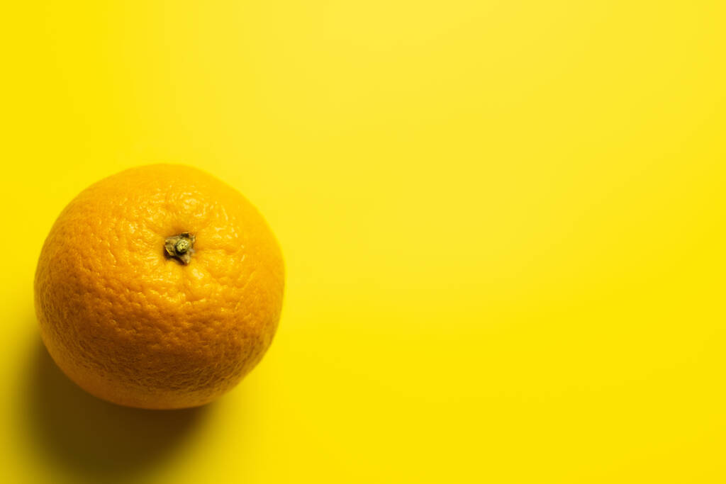 Draufsicht auf Orange mit Schatten auf gelbem Hintergrund  - Foto, Bild