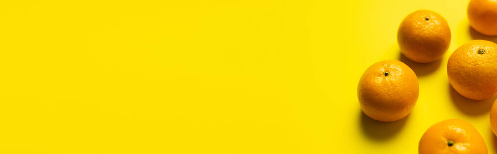 Hoge hoek weergave van mandarijnen op geel oppervlak, banner  - Foto, afbeelding