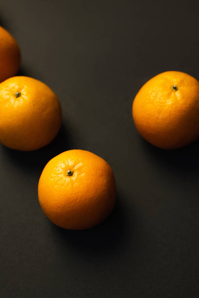 Draufsicht auf frische und natürliche Mandarinen auf schwarzem Hintergrund - Foto, Bild